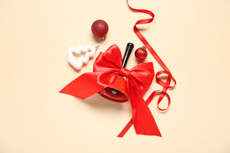 Christmas composition with red ribbon and bell on beige backgroundの写真素材