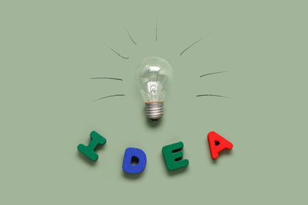 Light bulb with word IDEA made of wooden letters on green background. Business idea conceptの写真素材