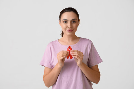 Young woman with red ribbon on white background. AID awareness concept