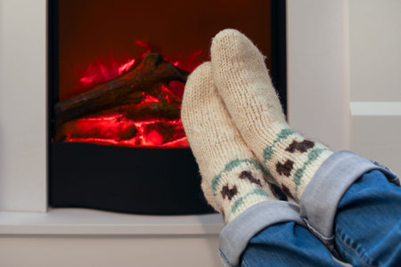 Woman in warm socks near fireplace at home on Christmas Eve