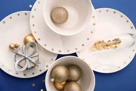 Beautiful table setting with Christmas balls and gift box on blue backgroundの写真素材
