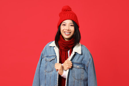 Young Asian woman in winter clothes on red backgroundの写真素材