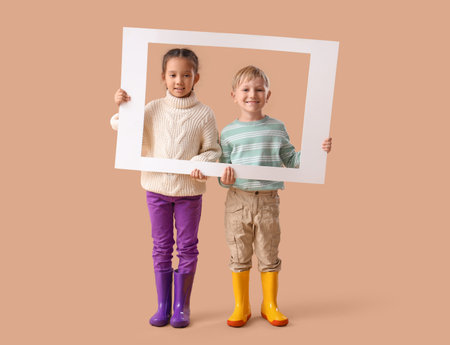 Little children in rubber boots with frame on beige backgroundの写真素材