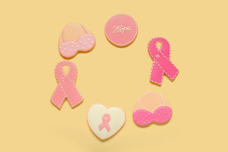Circle made of different pink cookies on yellow background. Breast cancer awareness conceptの写真素材