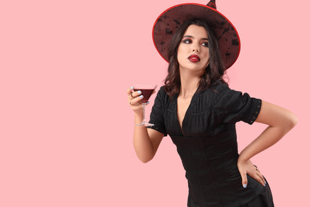 Young witch with drink on pink backgroundの写真素材