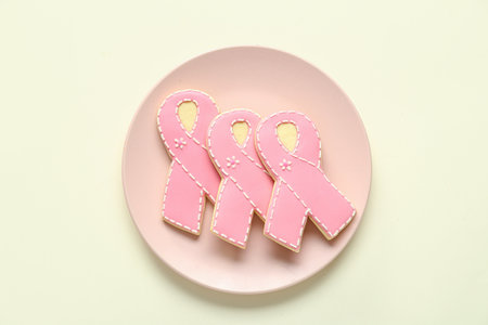 Plate with cookies in shape of pink ribbon on light yellow background. Breast cancer awareness conceptの写真素材