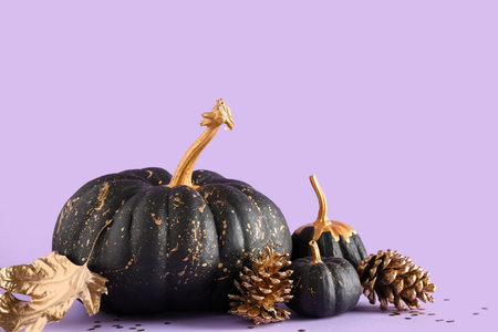 Painted pumpkins with golden cones and leaves on purple backgroundの写真素材