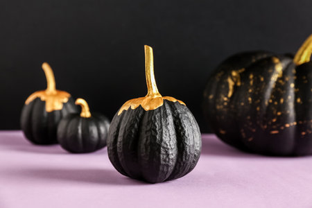 Painted pumpkins on purple table near black wallの写真素材