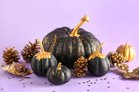 Painted pumpkins with golden cones and leaves on purple backgroundの写真素材