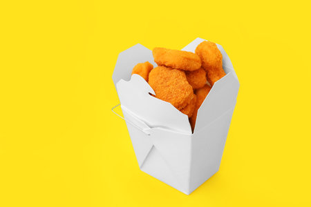 Paper box with tasty nuggets on yellow backgroundの写真素材