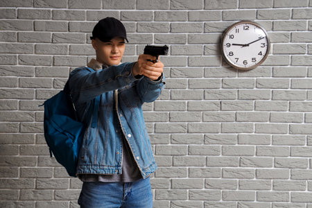 Male student with gun in hall. School shooting conceptの写真素材