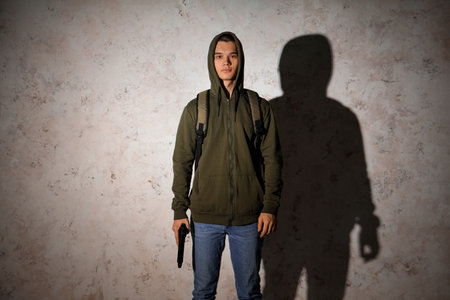 Male student with gun near grunge wallの写真素材