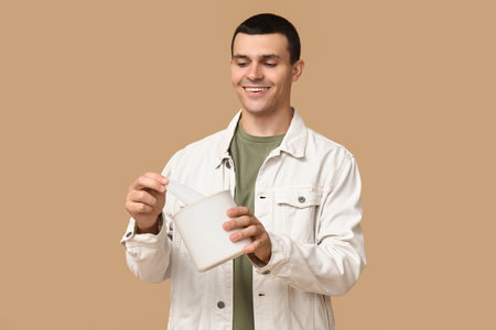 Ill young man with tissues on brown backgroundの写真素材
