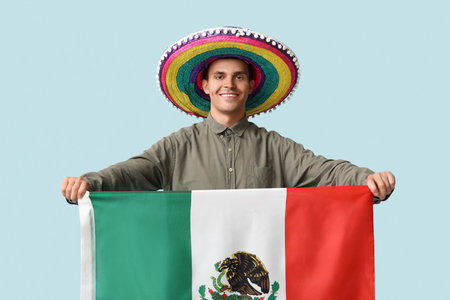 Handsome young man in sombrero with Mexican flag on blue backgroundの写真素材