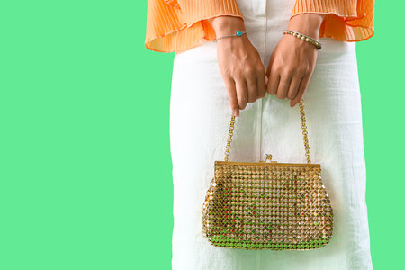 Beautiful young Asian woman with stylish bracelets and bag on green background, closeupの写真素材