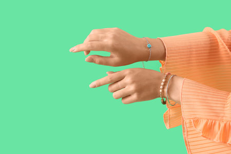 Beautiful young Asian woman with different stylish bracelets on green background, closeupの写真素材