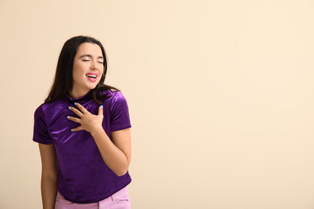 Beautiful happy young woman on beige backgroundの写真素材