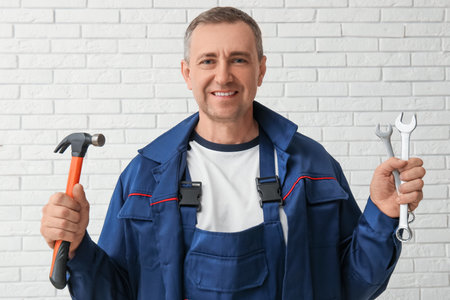 Portrait of male mechanic with tools on white brick backgroundの写真素材
