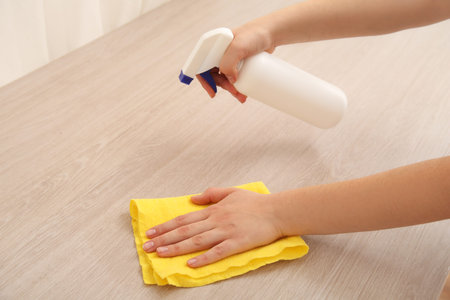 Young woman cleaning wooden table
