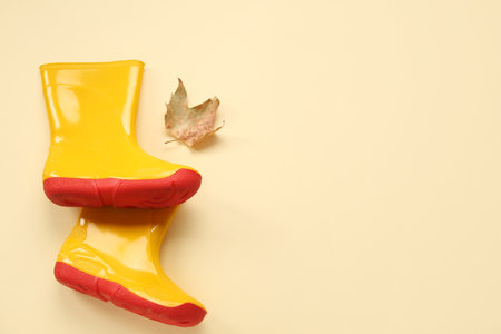 Yellow gumboots with autumn leaf on color backgroundの写真素材