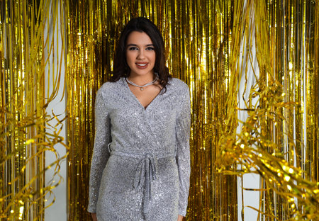 Beautiful young woman against golden tinselの写真素材