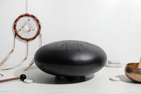 Glucophone with sticks, spa stones, tibetan singing bowl and dream catcher on white wooden table...