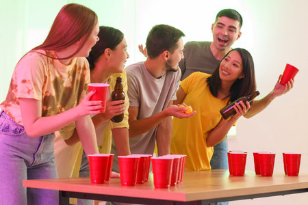 Group of young friends playing beer pong at party