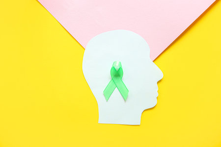 Paper human head with green awareness ribbon on color background. Mental Health Dayの写真素材