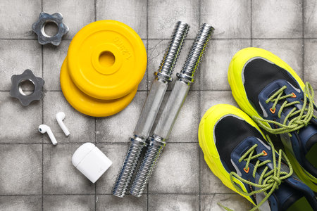 Barbell plates, shoes, grips, earphones and clamps on gray tile background