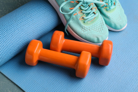 Dumbbells, yoga mat and shoes on blue