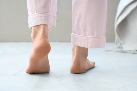 Barefoot woman walking on floor with heating in bedroom, back viewの写真素材