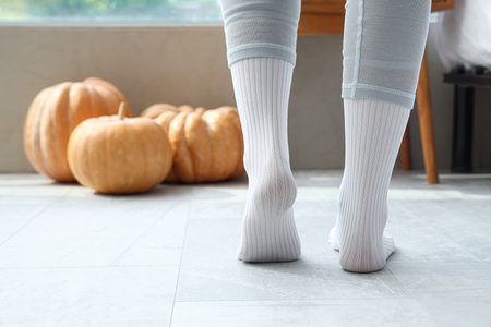 Woman in white socks walking on floor with heating at home, back viewの写真素材
