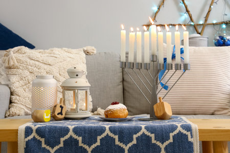 Menorah with donut, lanterns and dreidels for Hannukah on table in living roomの写真素材