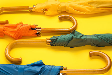 Different stylish umbrellas on yellow background