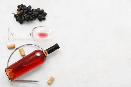 Glass and bottle of exquisite wine with grapes on white backgroundの写真素材