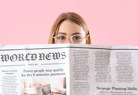 Beautiful young woman with newspaper on pink backgroundの写真素材