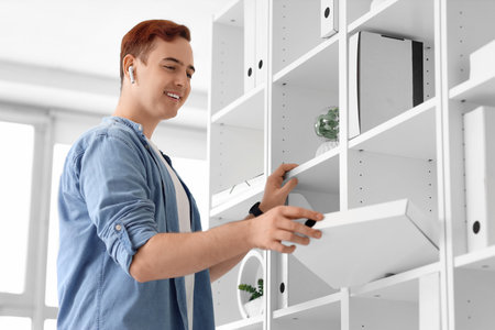 Young businessman taking folder from shelf in officeの写真素材