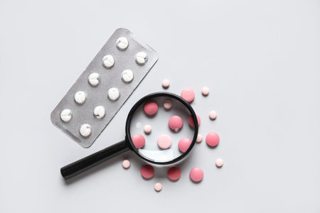Magnifier with different pills on gray background