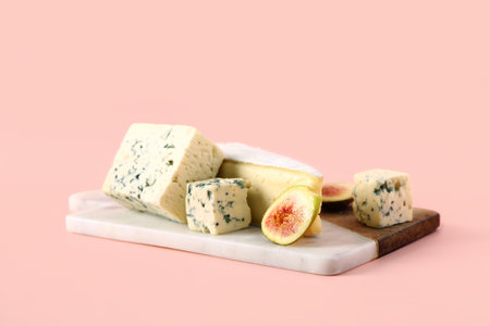 Board with tasty cheese and fig on pink backgroundの写真素材