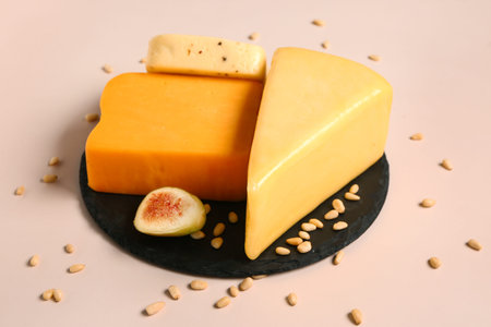 Board with tasty cheese, nuts and fig on beige background