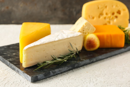 Board with tasty cheese on table, closeup