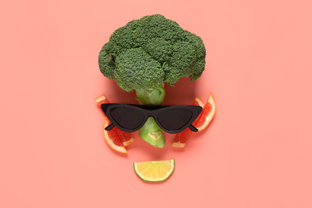 Funny face made of fresh broccoli, citrus fruits and sunglasses on color backgroundの写真素材