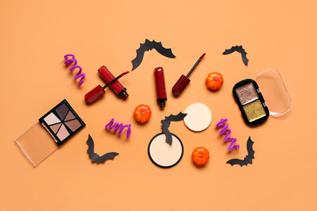 Lipsticks and different decorative cosmetics with Halloween decor on orange backgroundの写真素材