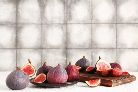 Plate and wooden board with fresh ripe figs on white table