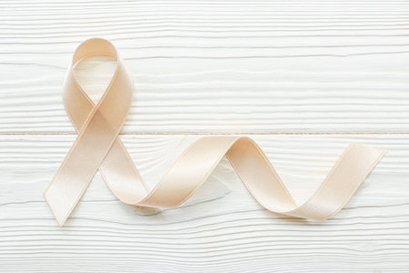 Beige ribbon on white wooden background. Uterine cancer awareness conceptの写真素材