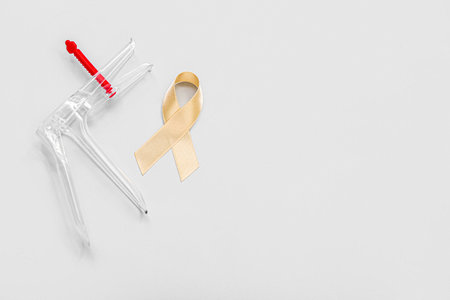 Beige ribbon with gynecological tool on light background. Uterine cancer awareness conceptの写真素材