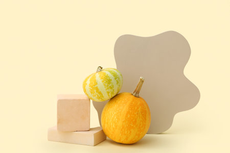 Decorative podiums with pumpkins on light yellow backgroundの写真素材