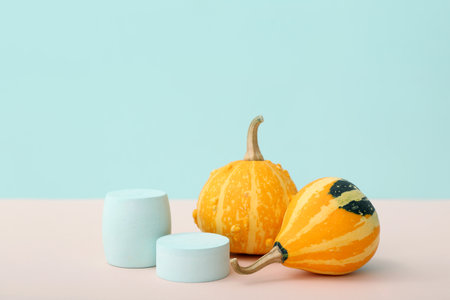 Decorative plaster podiums and pumpkins on pink table against blue backgroundの写真素材