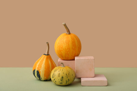 Decorative plaster podiums and pumpkins on light green table against beige background