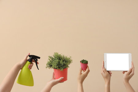 Women with blank tablet computer, plants and spray bottle on beige backgroundの写真素材